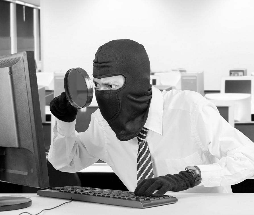 A person wearing a mask in front of a computer